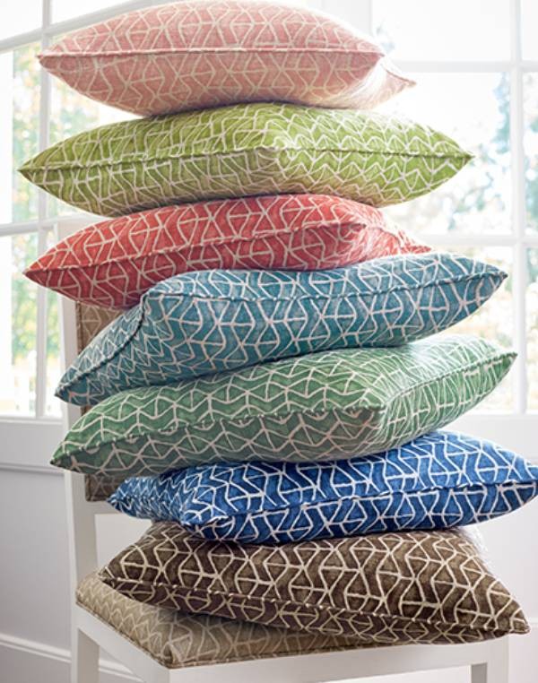 Pile of colorful pillows stacked on a chair with patterns from Sojourn StonyBrook Color series at Gables New York near Staten Island, NY
